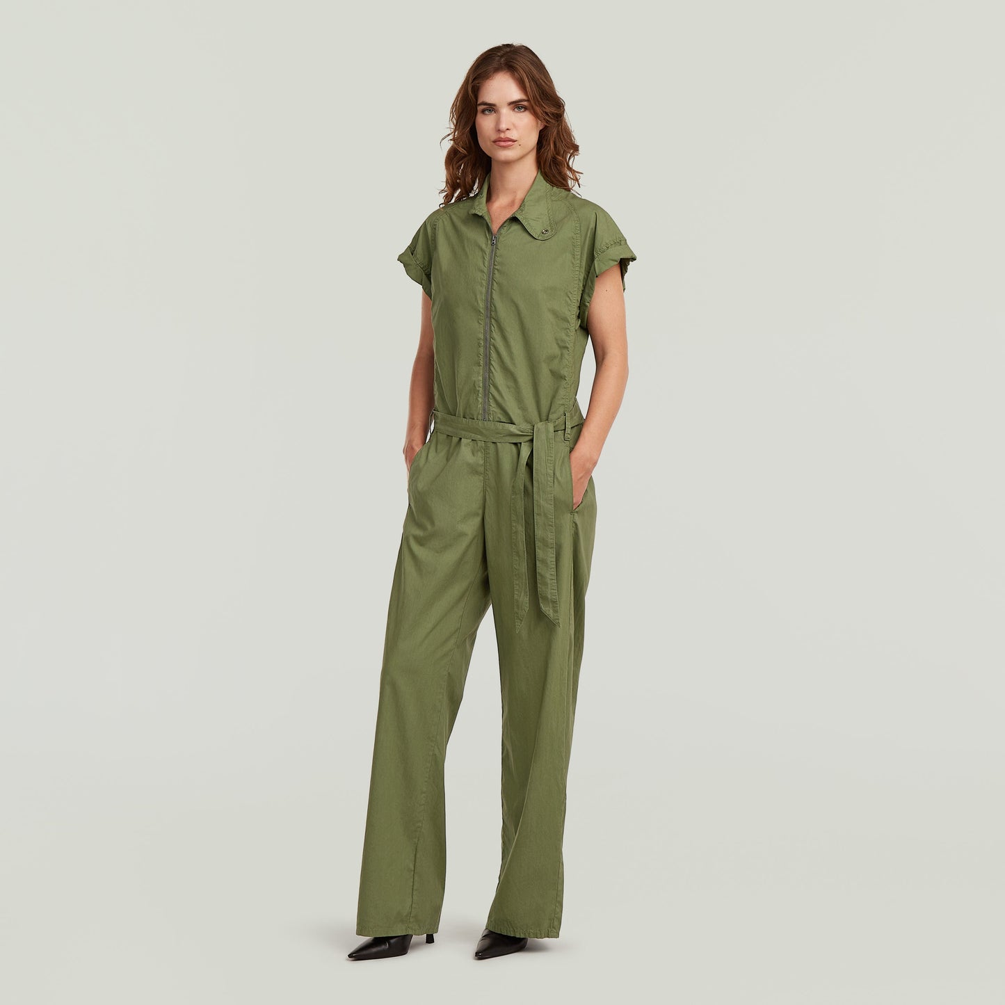 summer jumpsuit with high waist in green with short sleeves and long pants, styled with a belt.