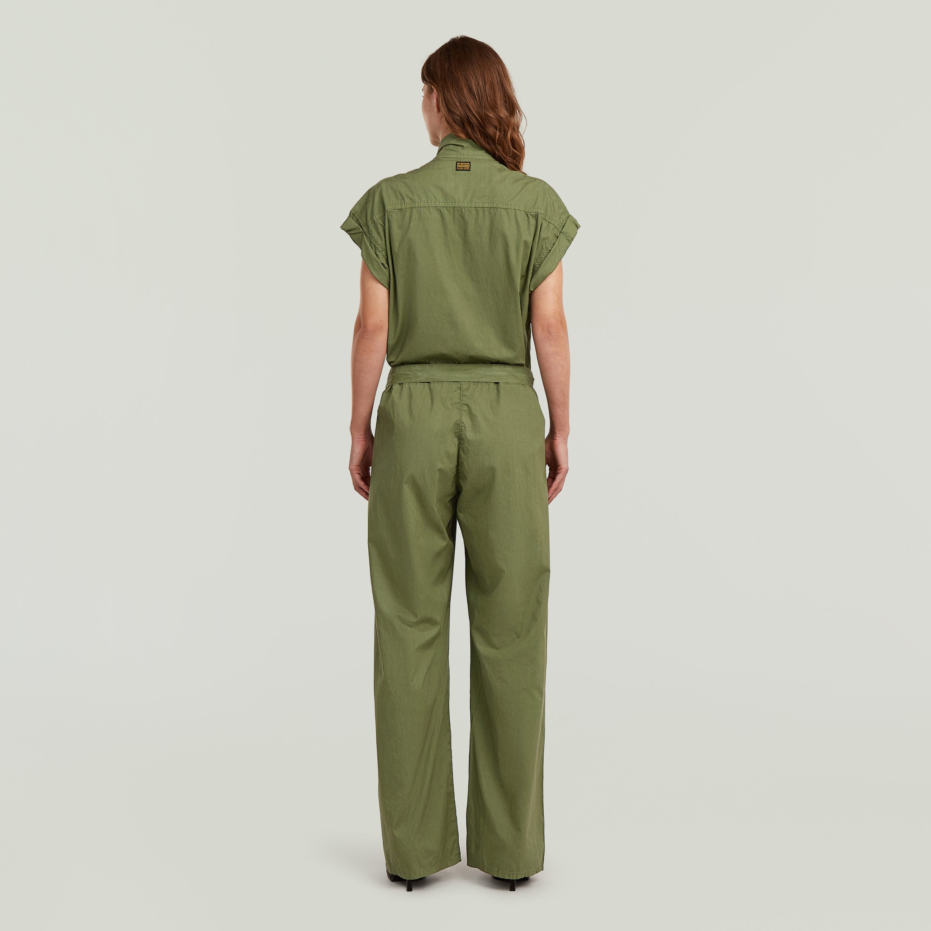 Mujer de espaldas vistiendo un summer jumpsuit with high waist de color verde, con diseño ligero y elegante.