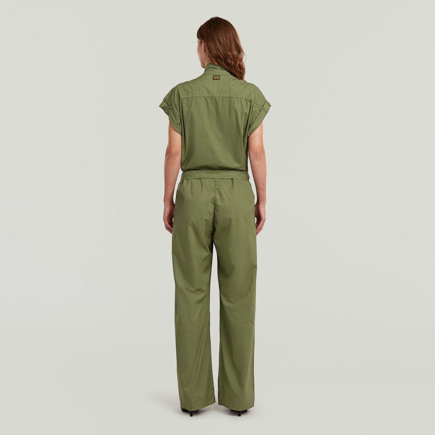 Mujer de espaldas vistiendo un summer jumpsuit with high waist de color verde, con diseño ligero y elegante.