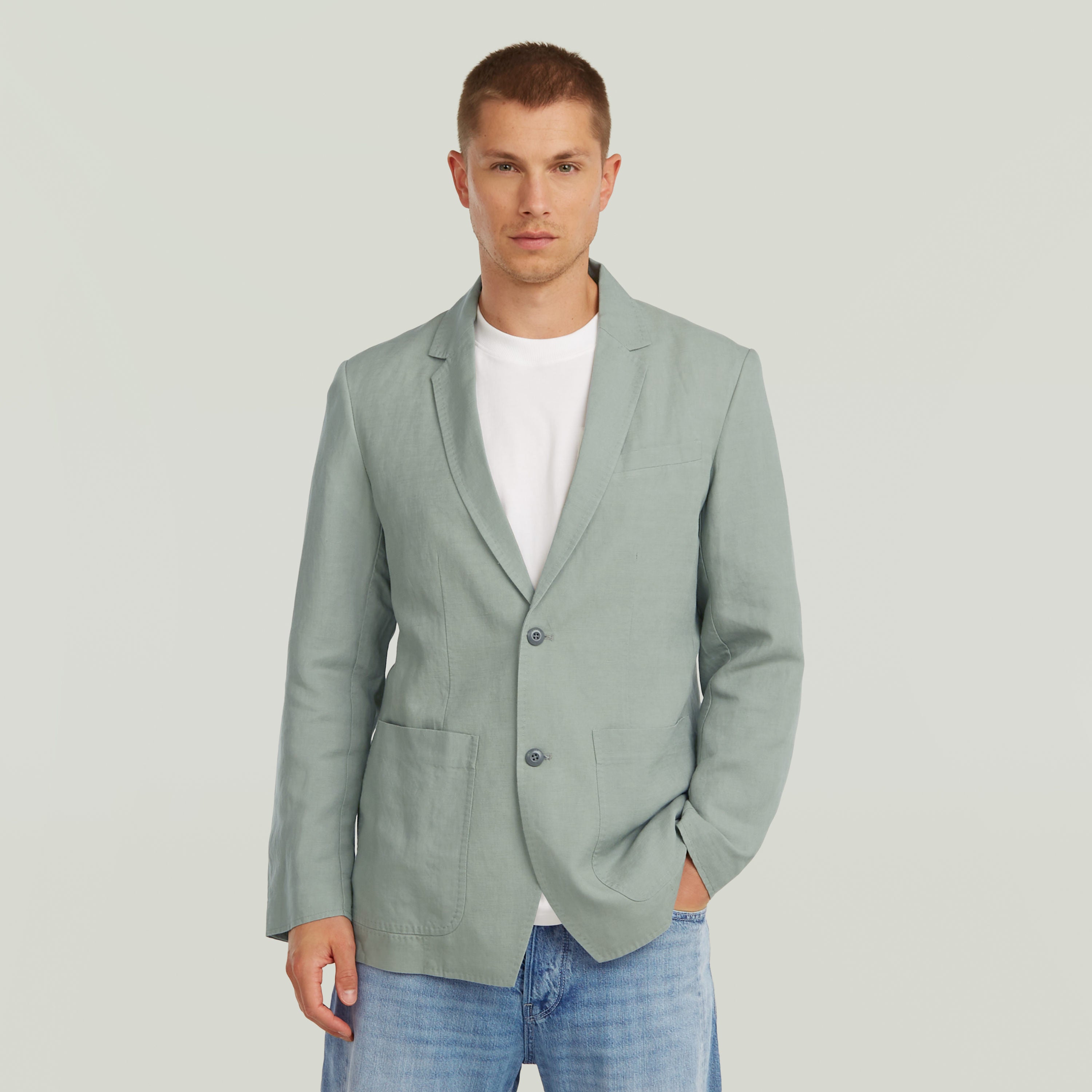 Hombre vistiendo un blazer verde ligero, diseño clásico con solapa y cierre de botones, estilo versátil.