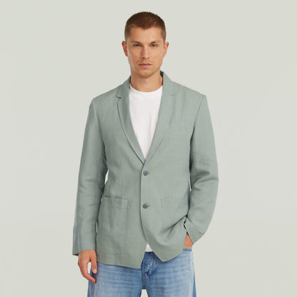Hombre vistiendo un blazer verde ligero, diseño clásico con solapa y cierre de botones, estilo versátil.