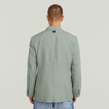 Back view of a man wearing a lightweight green blazer, showcasing its refined design and breathable fabric.