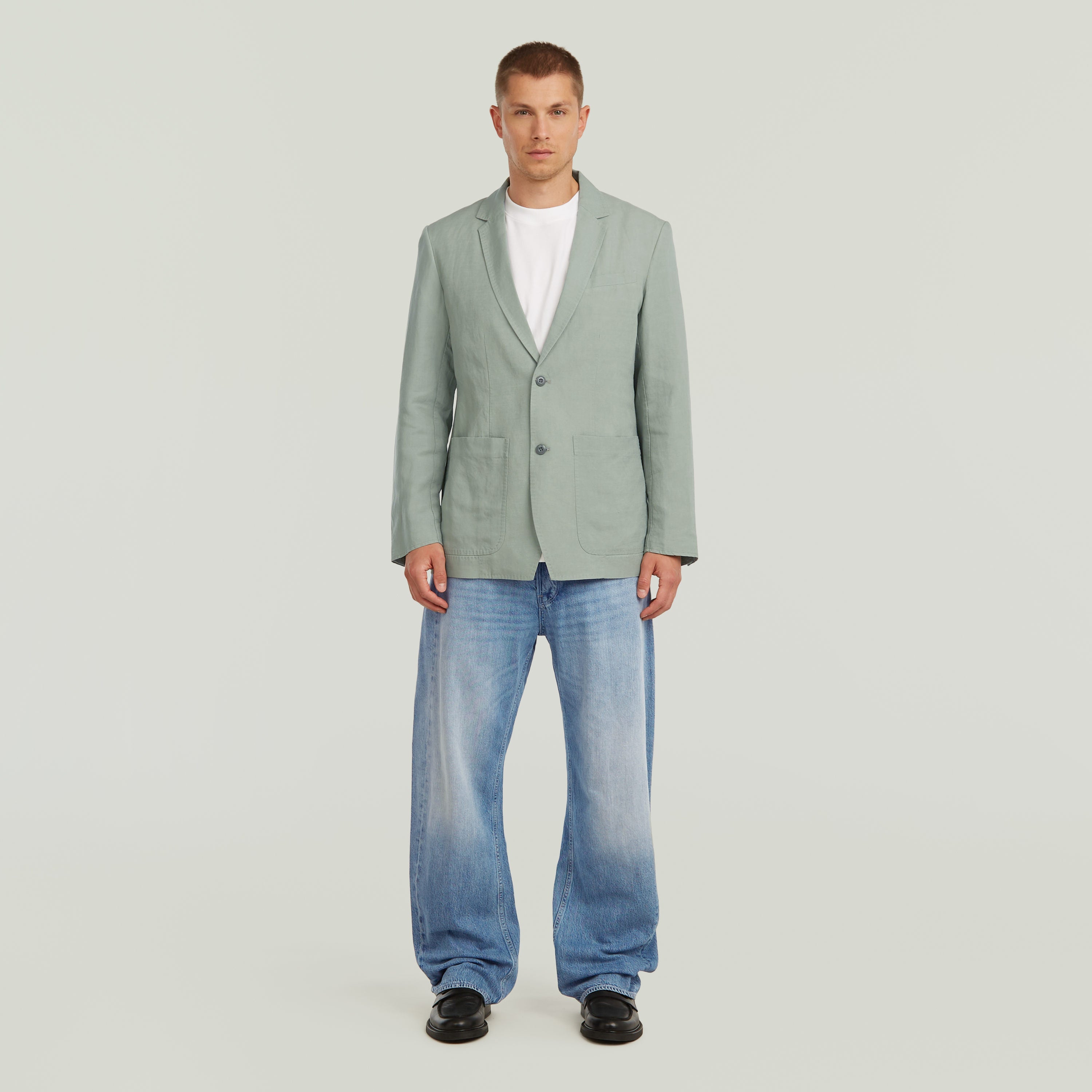 Model wearing a lightweight green blazer paired with jeans, showcasing a stylish summer look.