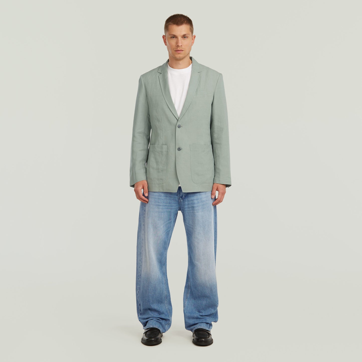 Model wearing a lightweight green blazer paired with jeans, showcasing a stylish summer look.