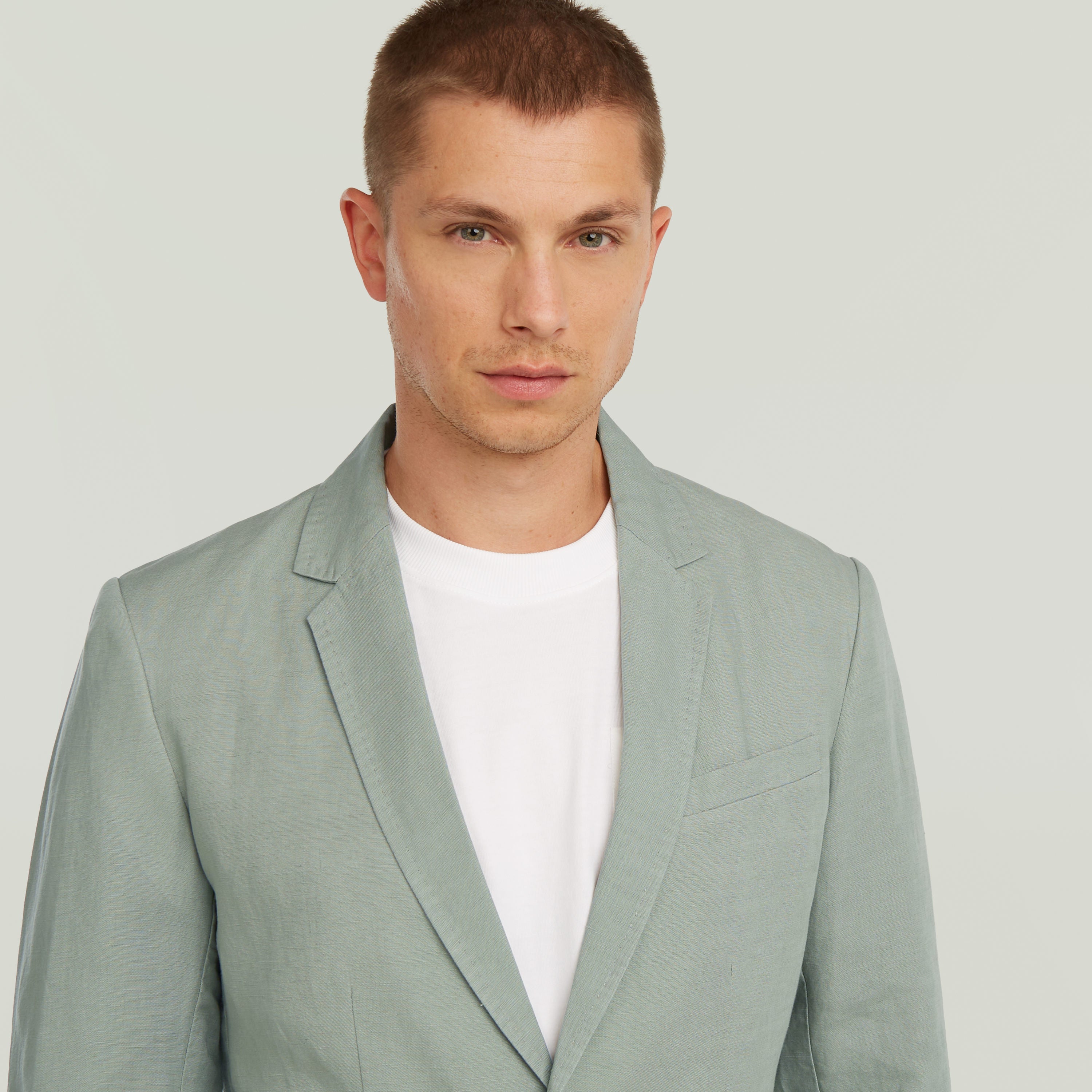 Stylish man wearing a lightweight green blazer with a classic design featuring notched lapels.