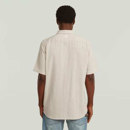 Hombre de espaldas vistiendo una camisa one pocket regular de color blanco con diseño clásico y moderno.