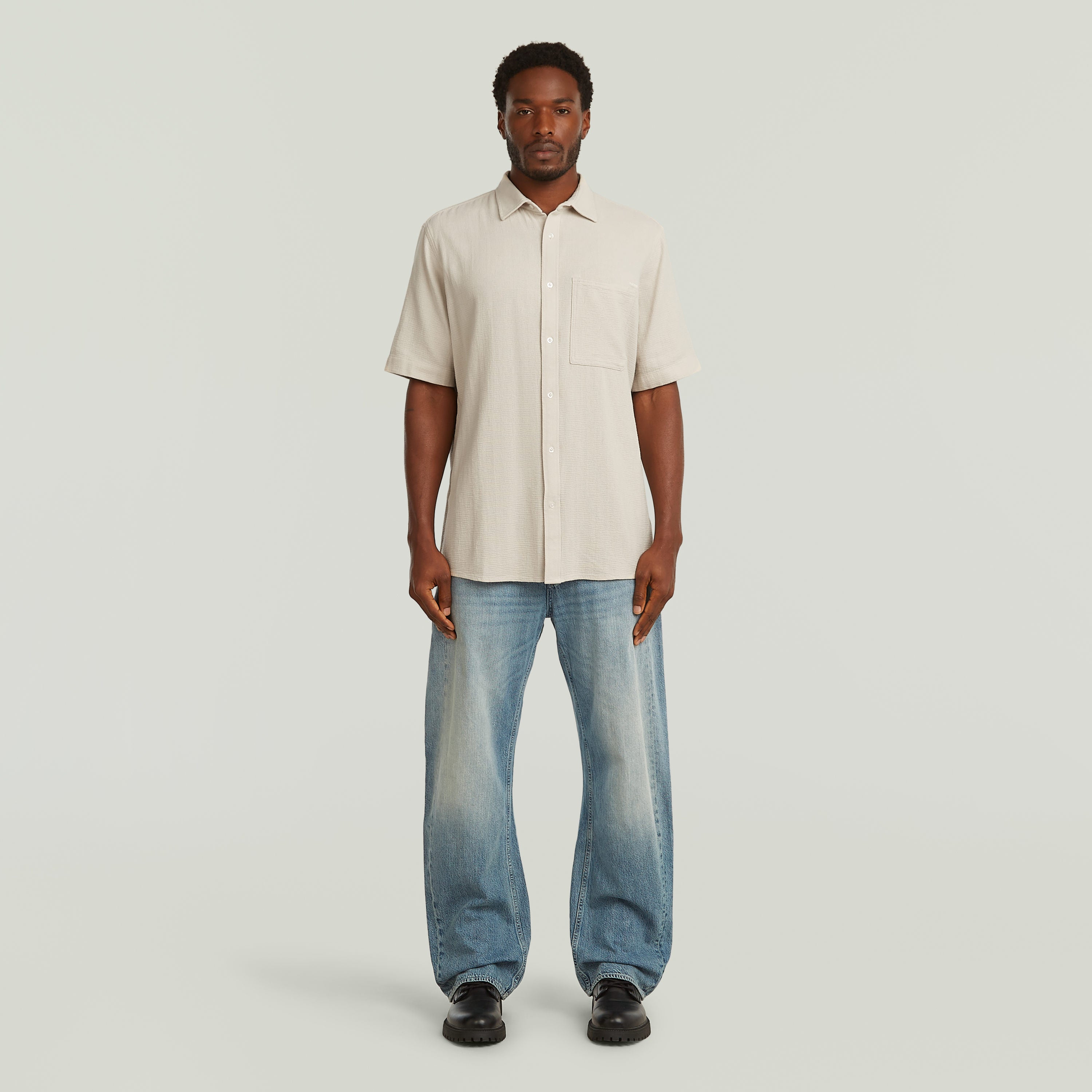 Modelo usando una camisa One Pocket Regular color blanco con jeans, estilo casual y moderno.