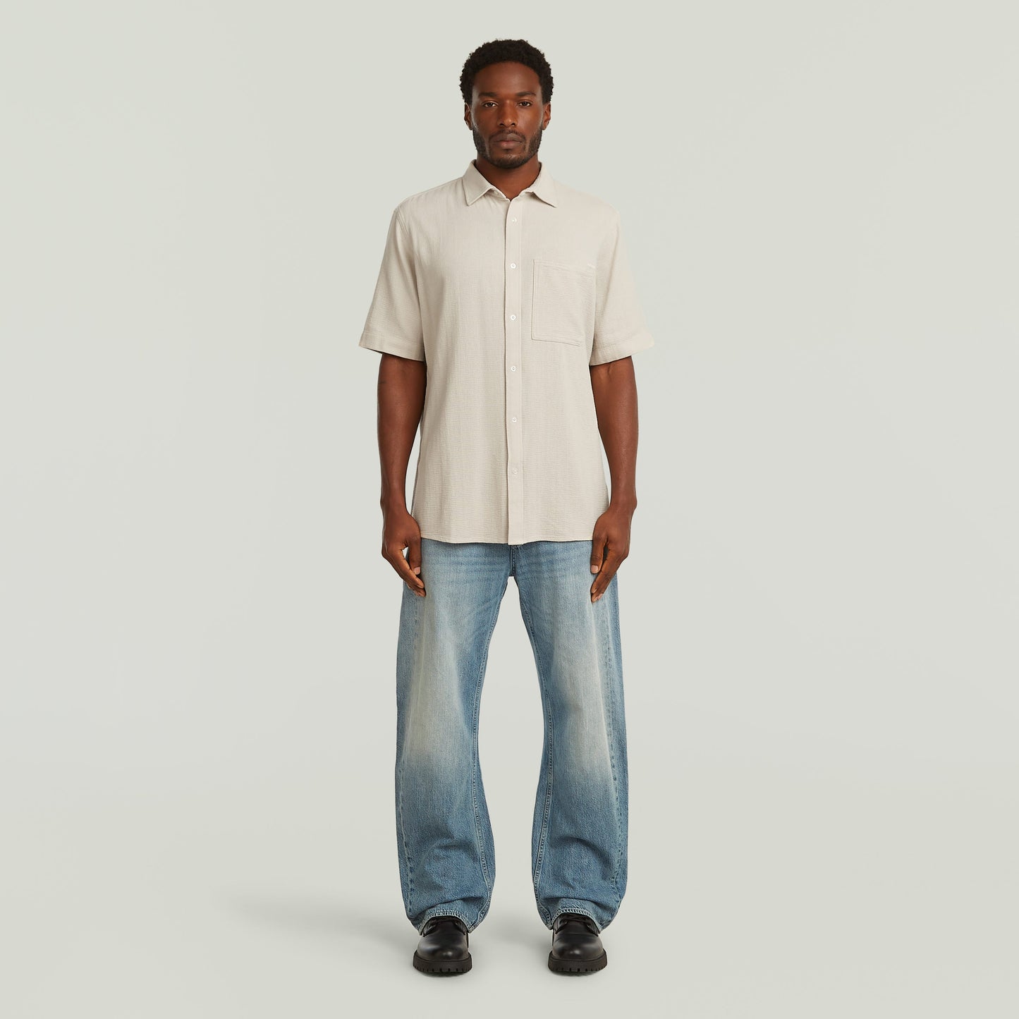 Modelo usando una camisa One Pocket Regular color blanco con jeans, estilo casual y moderno.