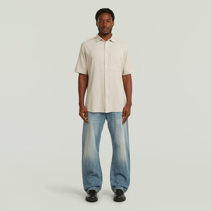 Modelo usando una camisa One Pocket Regular color blanco con jeans, estilo casual y moderno.