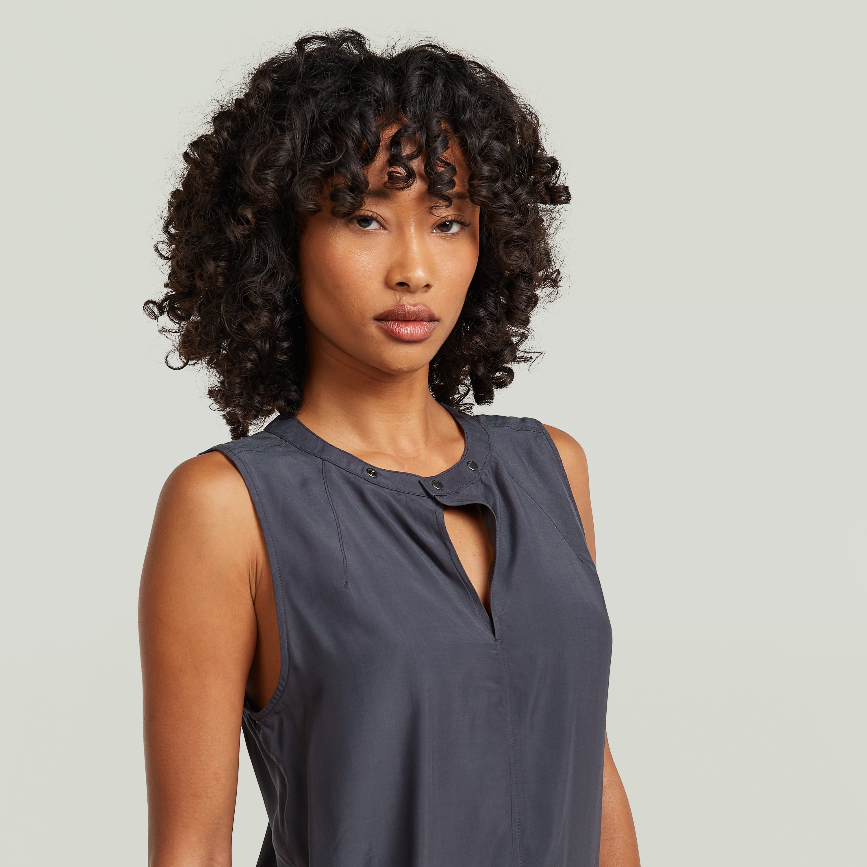 moderna camiseta sin mangas con cuello alzado en color gris, con diseño limpio y moderno.