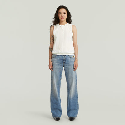 Camiseta sin mangas de alto cuello en algodón blanco, combinada con jeans de corte amplio.