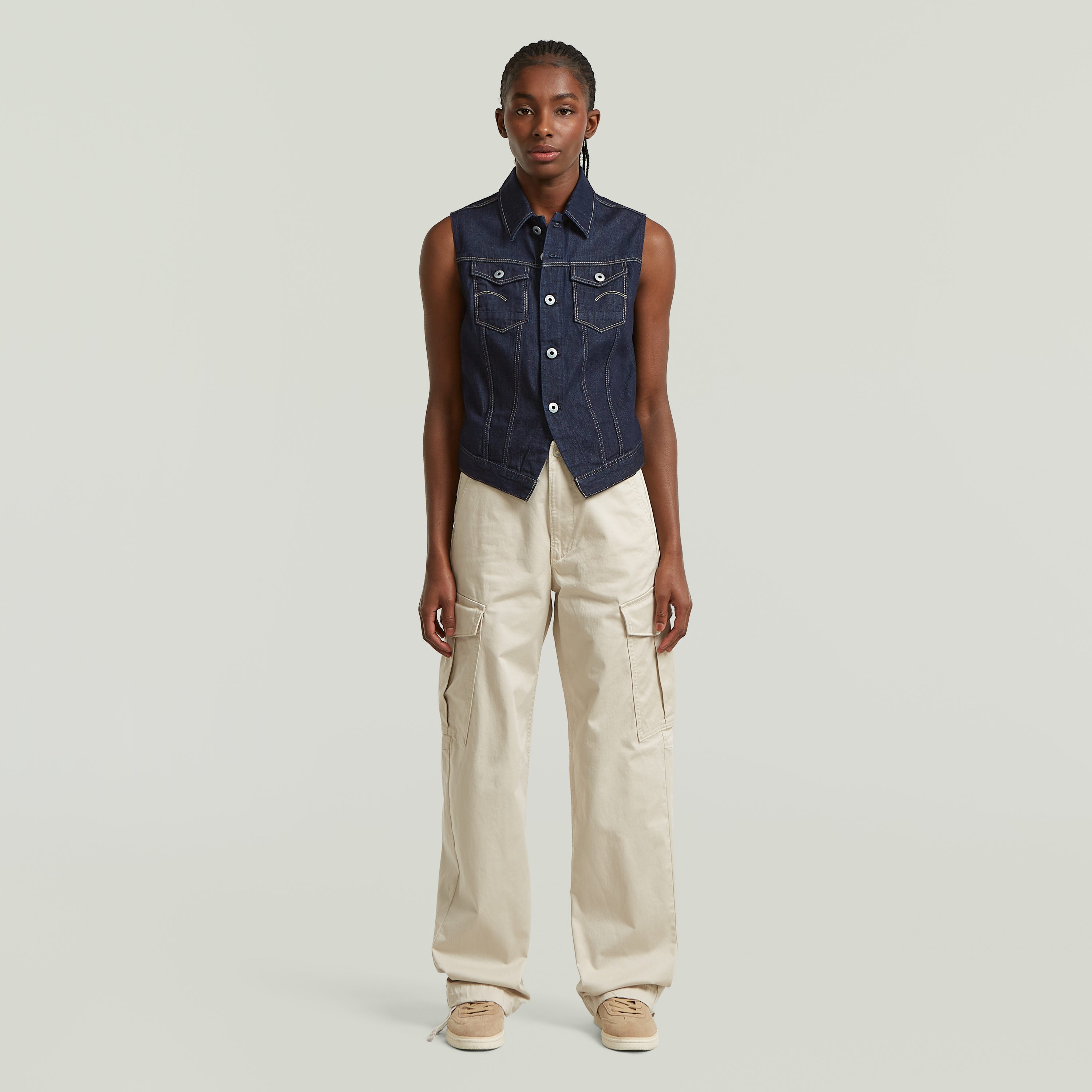 Modelo usando un chaleco Pitched Hem Slim fit denim vest, con botones y cuello de camisa, color azul oscuro.