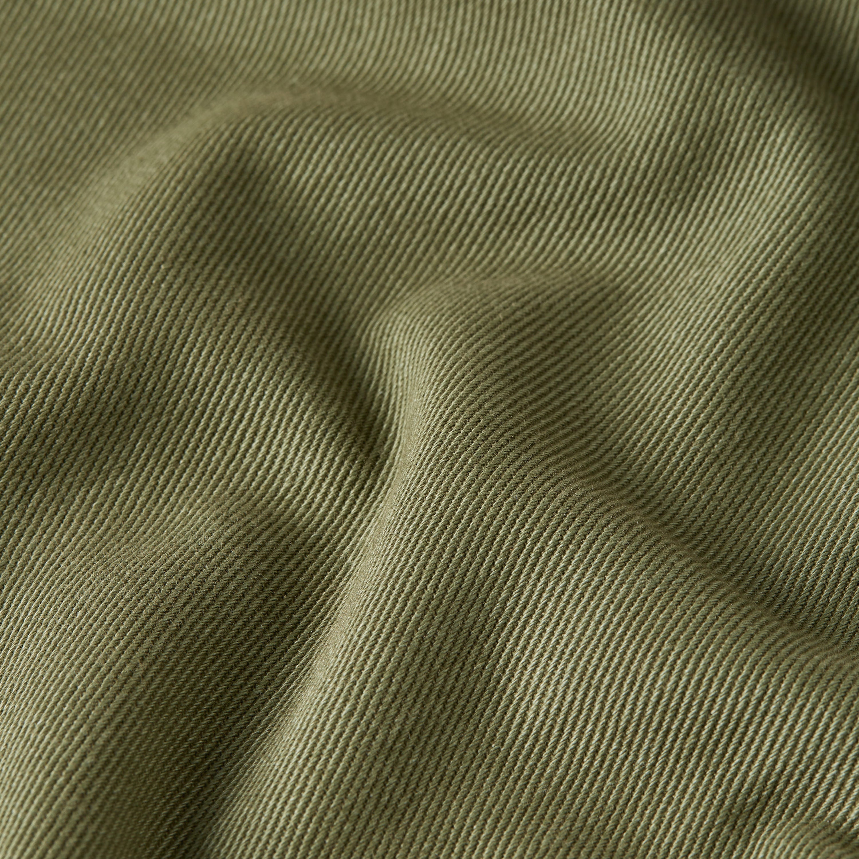 Texture of high-waisted chino fatigue pants in a soft, olive green color.
