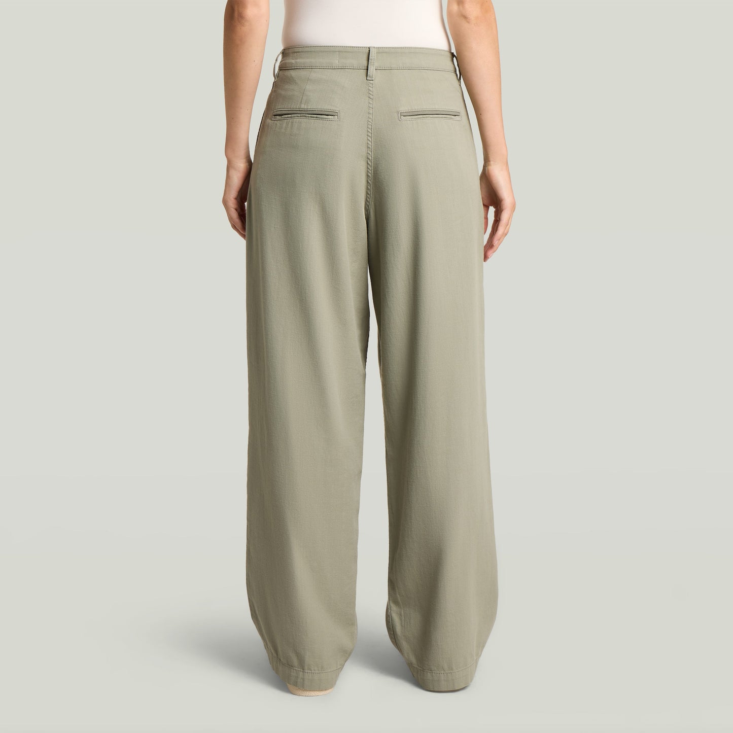 Vista trasera de pantalones pleated chino, diseño clásico en color verde con bolsillos traseros.