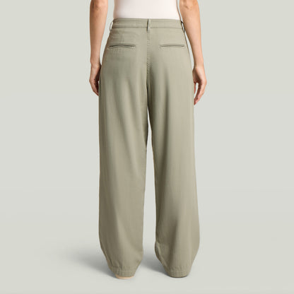 Vista trasera de pantalones pleated chino, diseño clásico en color verde con bolsillos traseros.