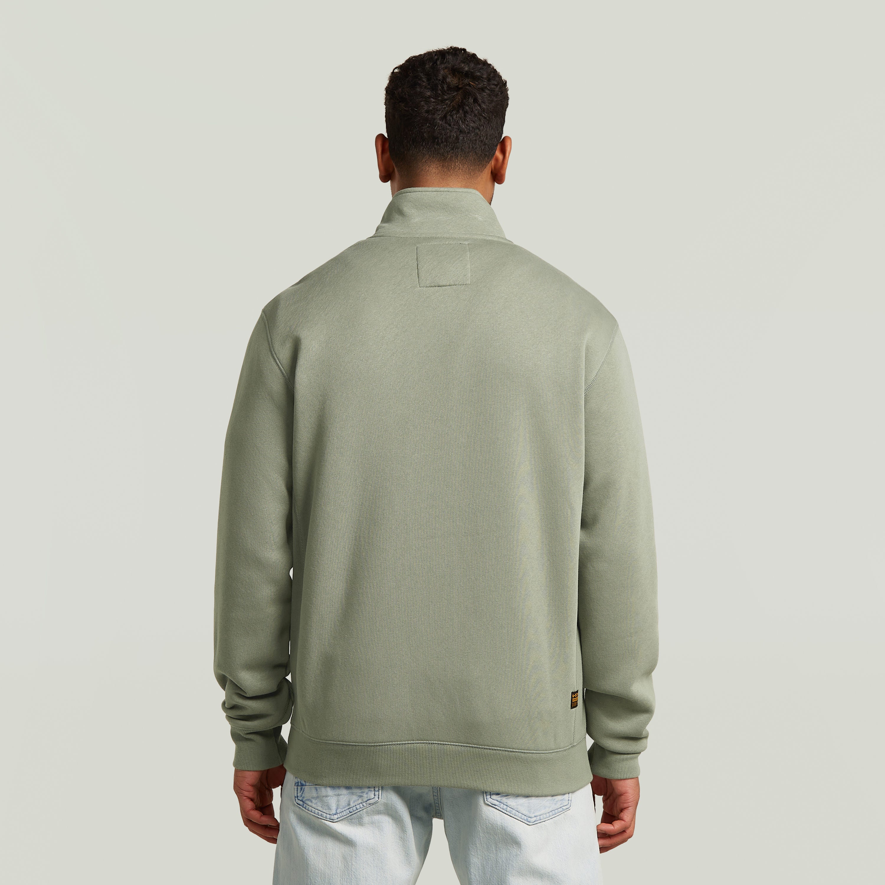 Hombre viendo la parte trasera de la chaqueta deportiva Premium Core Track en color verde.