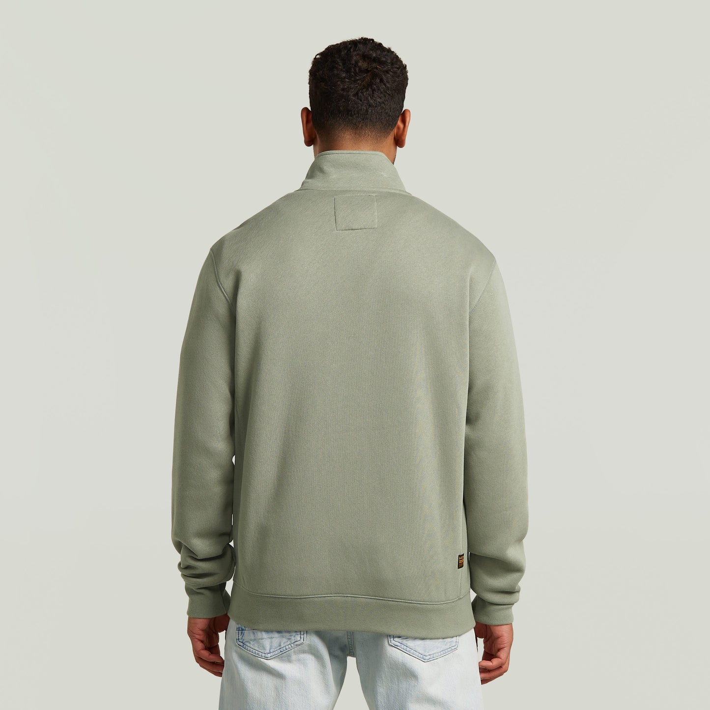 Hombre viendo la parte trasera de la chaqueta deportiva Premium Core Track en color verde.