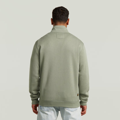 Hombre viendo la parte trasera de la chaqueta deportiva Premium Core Track en color verde.