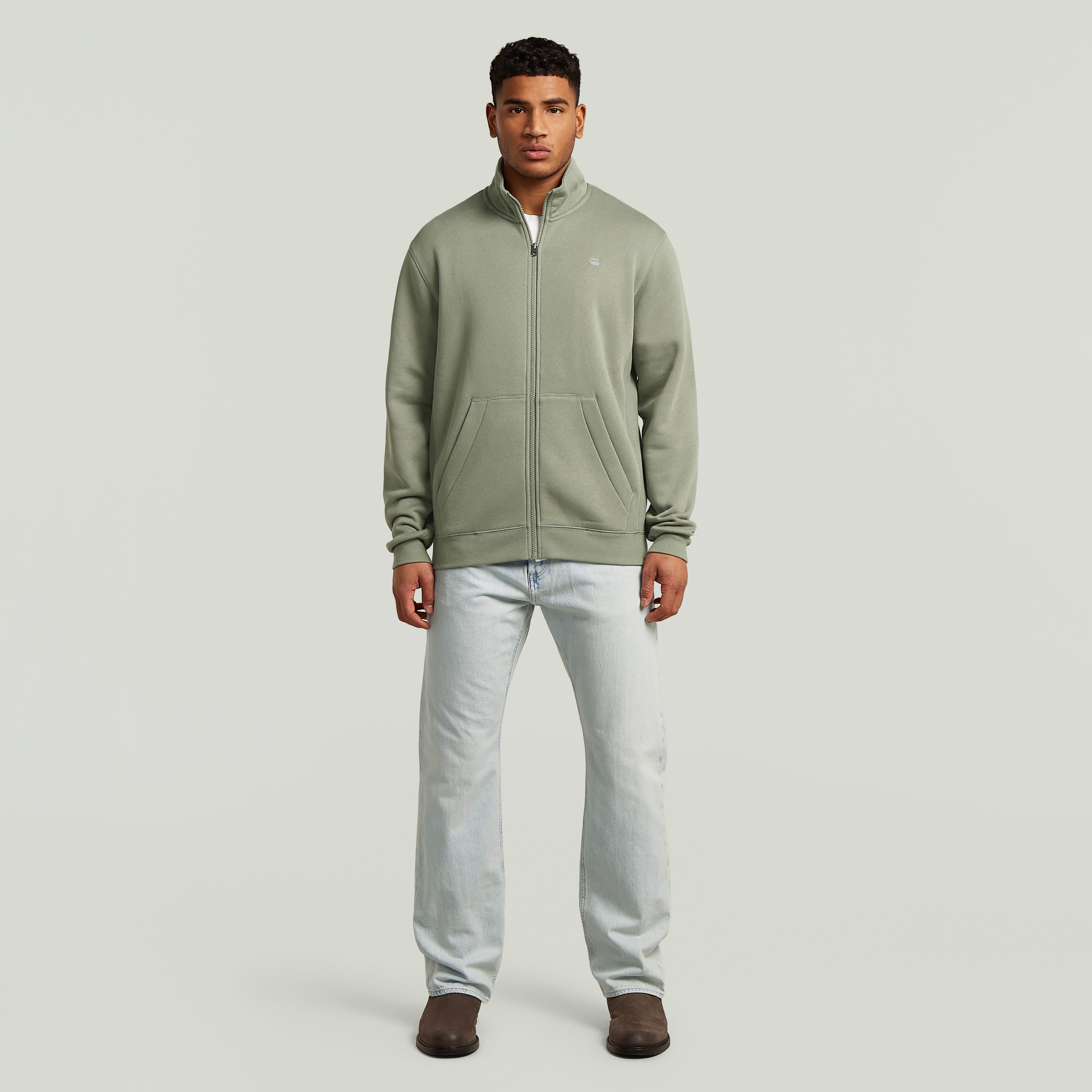 Hombre usando chaqueta deportiva Premium Core Track color verde con diseño clásico y cierre de cremallera.