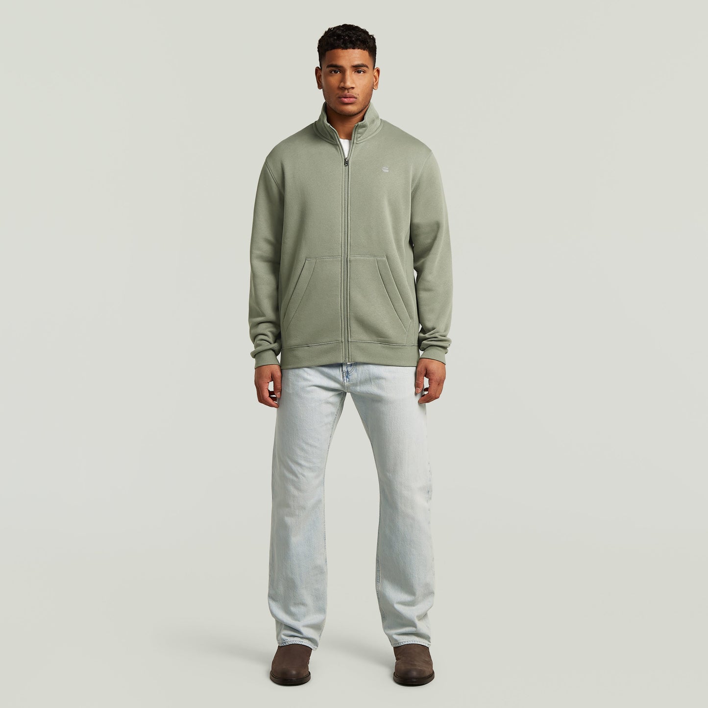Hombre usando chaqueta deportiva Premium Core Track color verde con diseño clásico y cierre de cremallera.