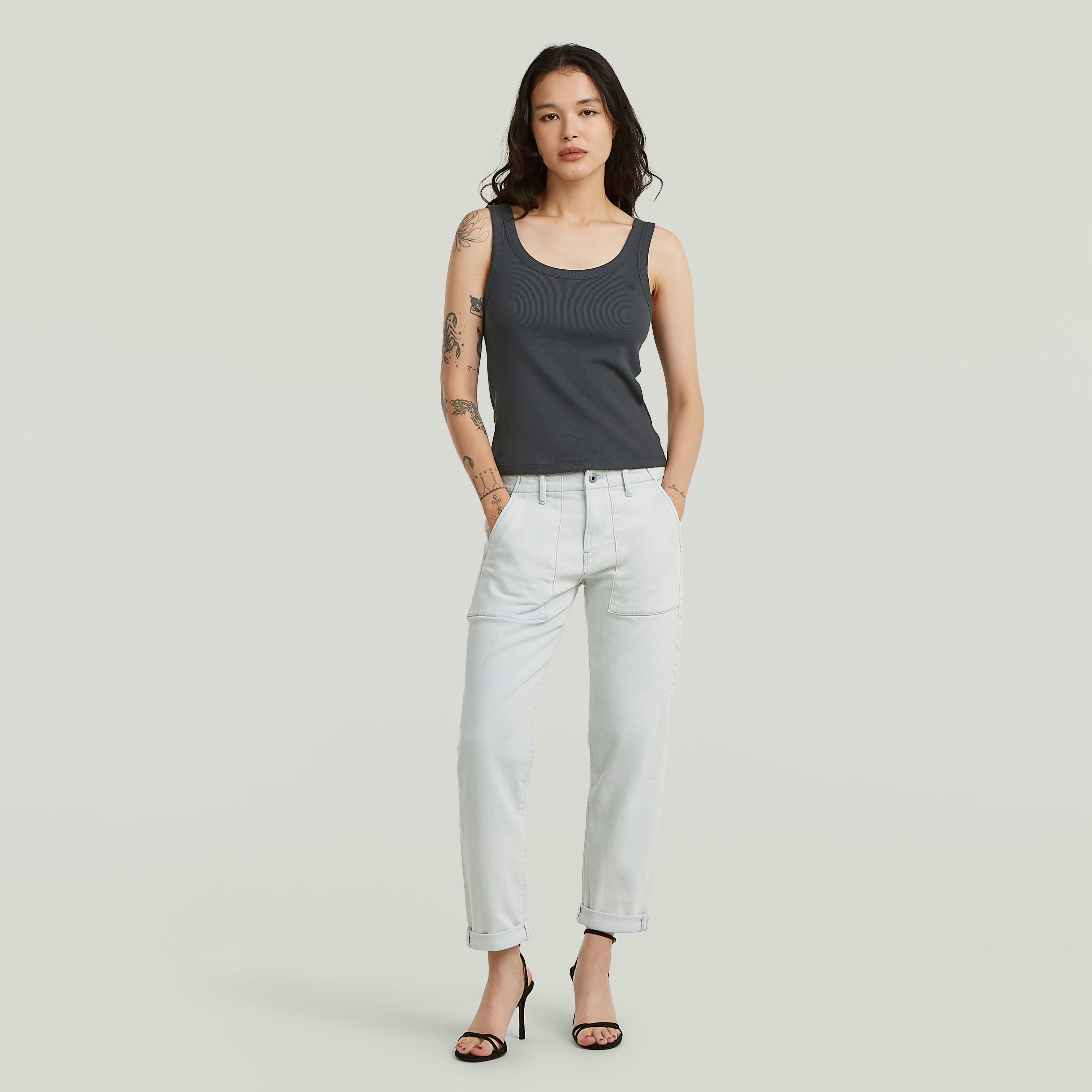 Mujer luciendo Jeans Kate Boyfriend Fatigue, estilo holgado y cómodo, con camiseta sin mangas y tacones.