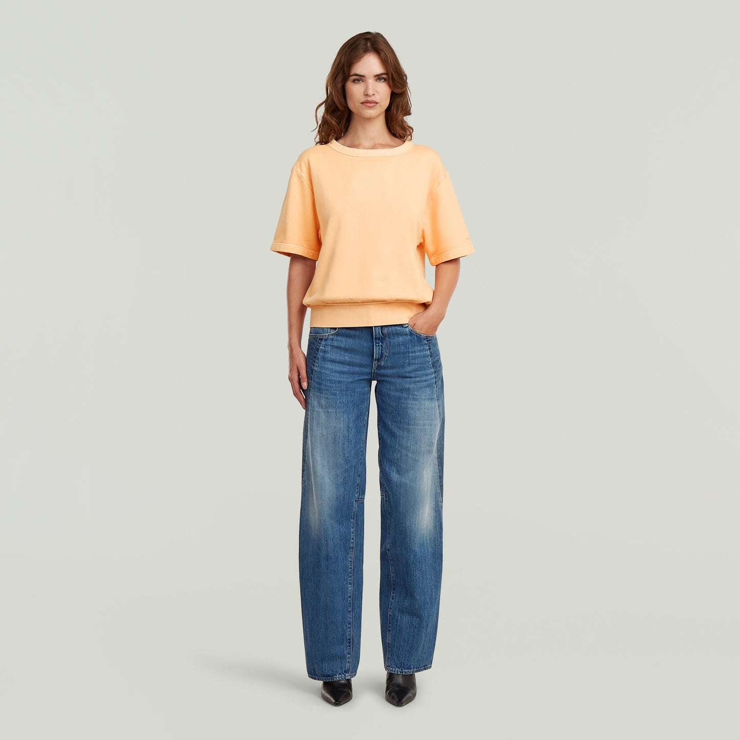 Woman wearing two-tone loose fit jeans with an orange top, showcasing relaxed and stylish attire.