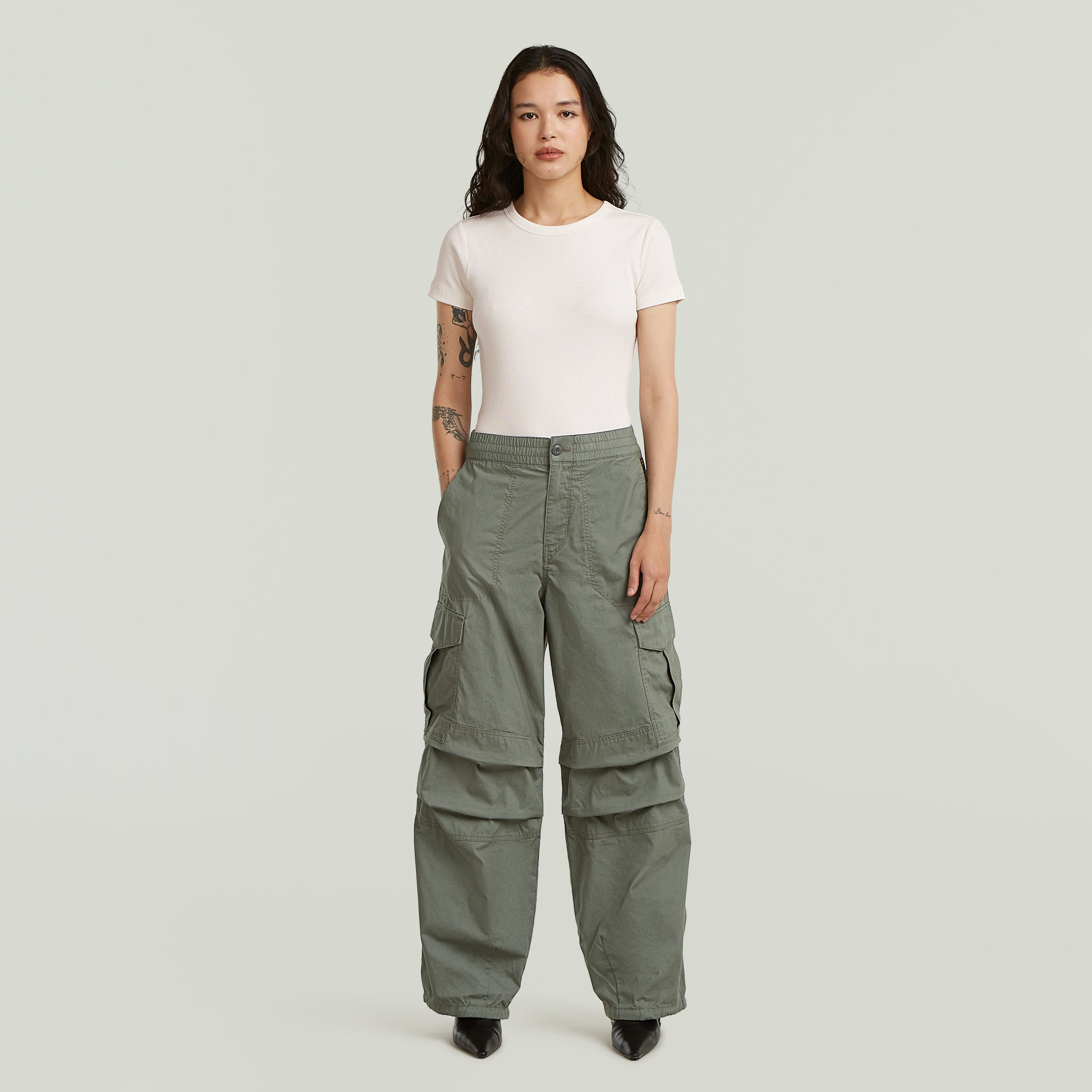 Modelo usando pantalones wide leg cargo de color verde con camiseta básica y tacones.