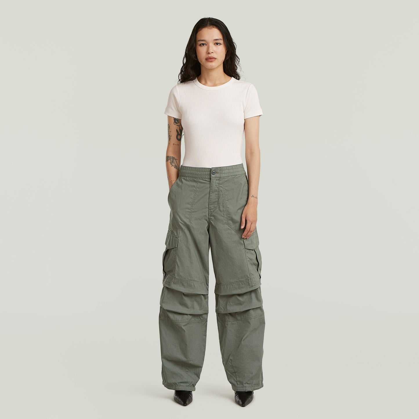 Modelo usando pantalones wide leg cargo de color verde con camiseta básica y tacones.