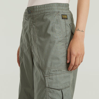 Dettaglio dei pantaloni wide leg cargo con tasche laterali e chiusura bottone in colore verde.