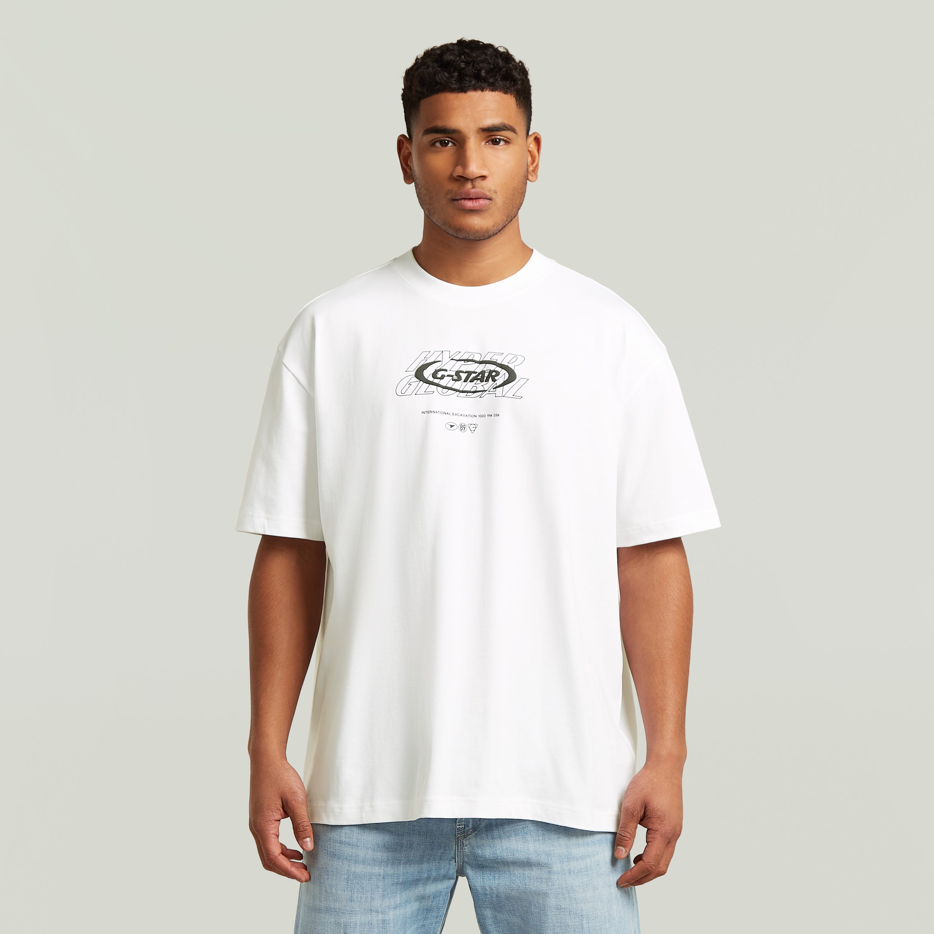 Hombre usando una camiseta blanca, camiseta gráfica relajada, estilo moderno y corte suelto.