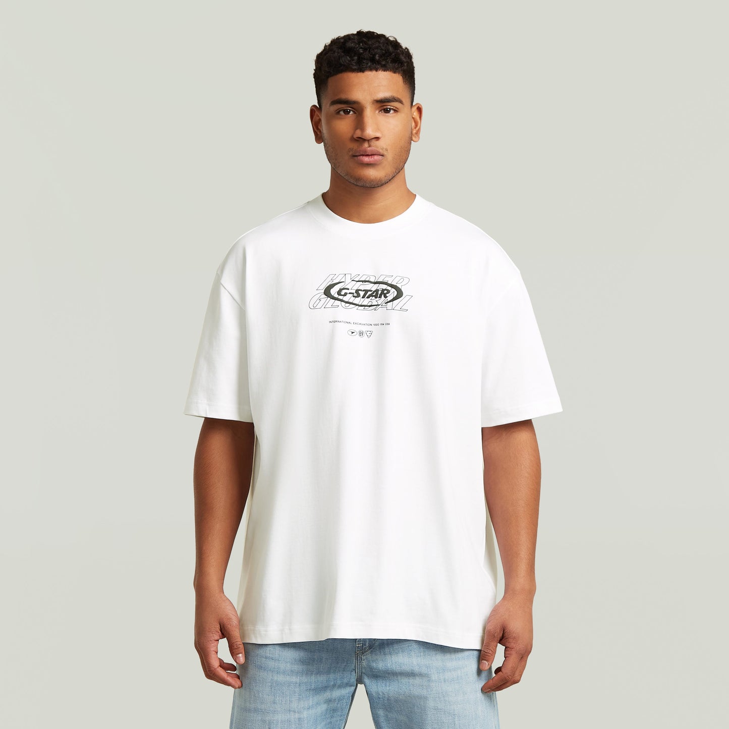 Hombre usando una camiseta blanca, camiseta gráfica relajada, estilo moderno y corte suelto.