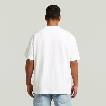 Model wearing a white relaxed graphic t-shirt, viewed from the back, showcasing the relaxed fit and comfortable design.
