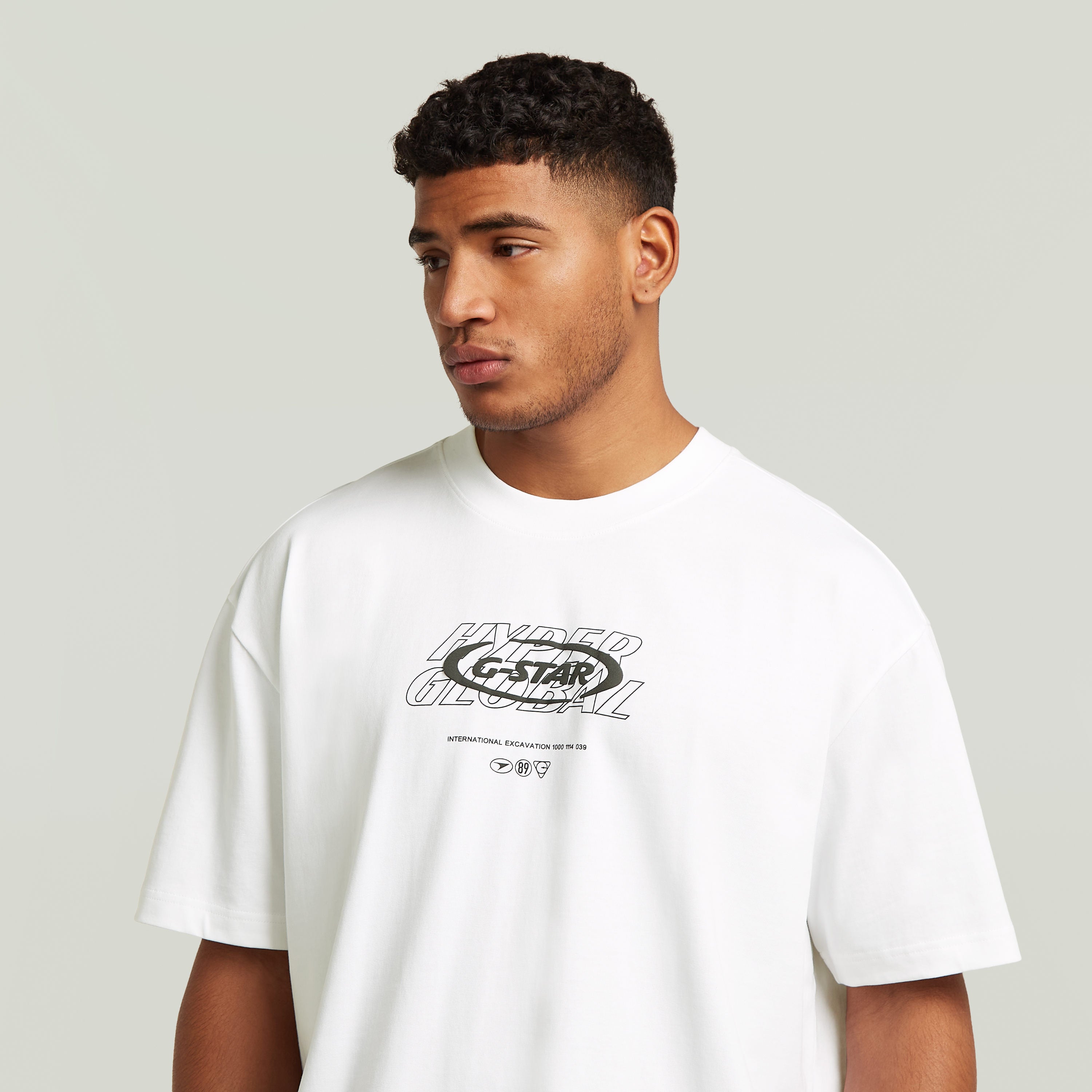 Hombre usando una camiseta Hyper Graphic Relaxed blanca, estilo relajado con estampado gráfico en el pecho, relaxed graphic t-shirt.