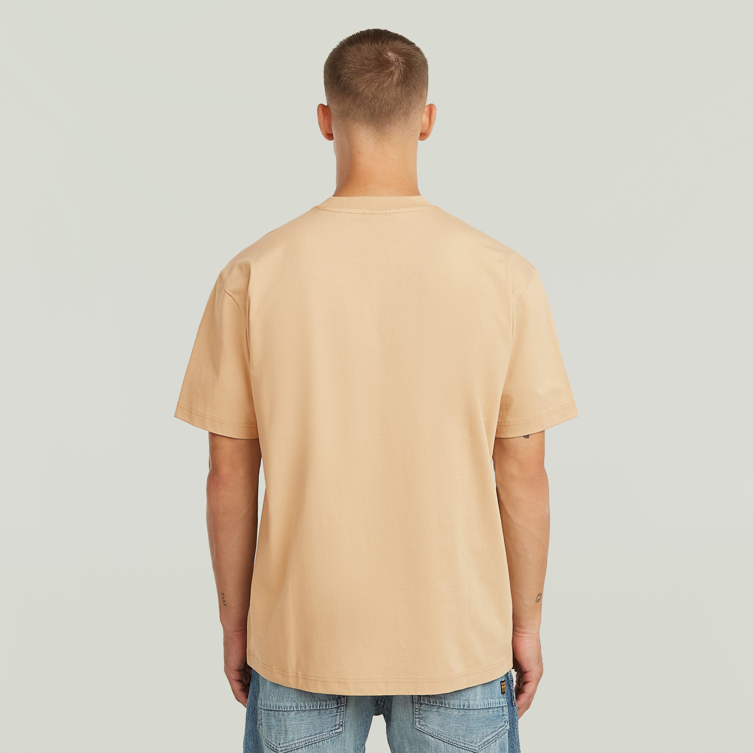 Camiseta beige de corte relajado, vista trasera, relajada, con cuello redondo, 100% algodón ecológico, relaxed graphic t-shirt.