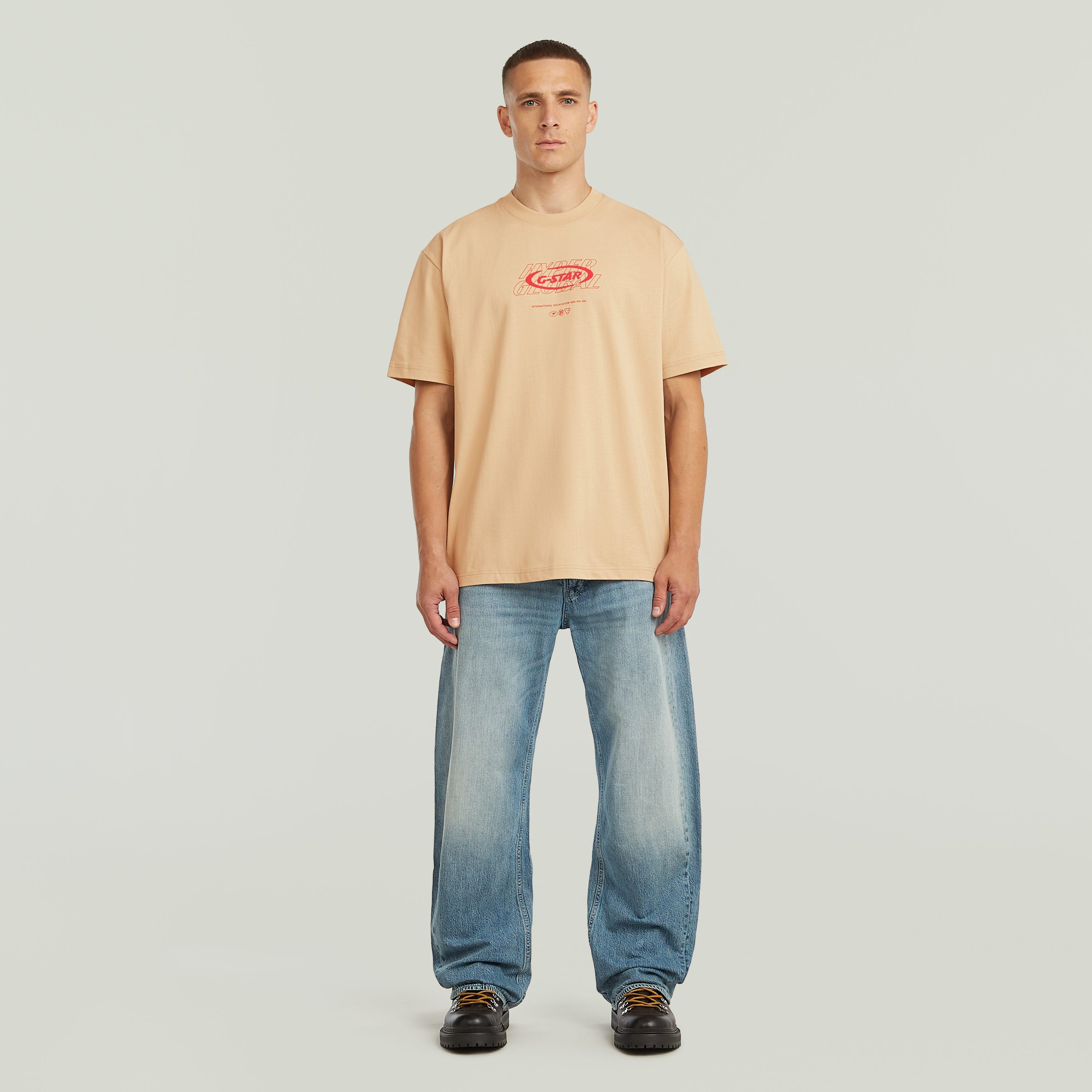 Hombre usando una camiseta Hyper Graphic Relaxed color beige, relajada y cómoda, enfocada en la relaxed graphic t-shirt.