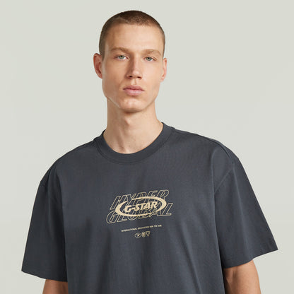 Modelo luciendo una camiseta Hyper Graphic Relaxed, relaxed fit graphic t-shirt color gris con estampado en el pecho.