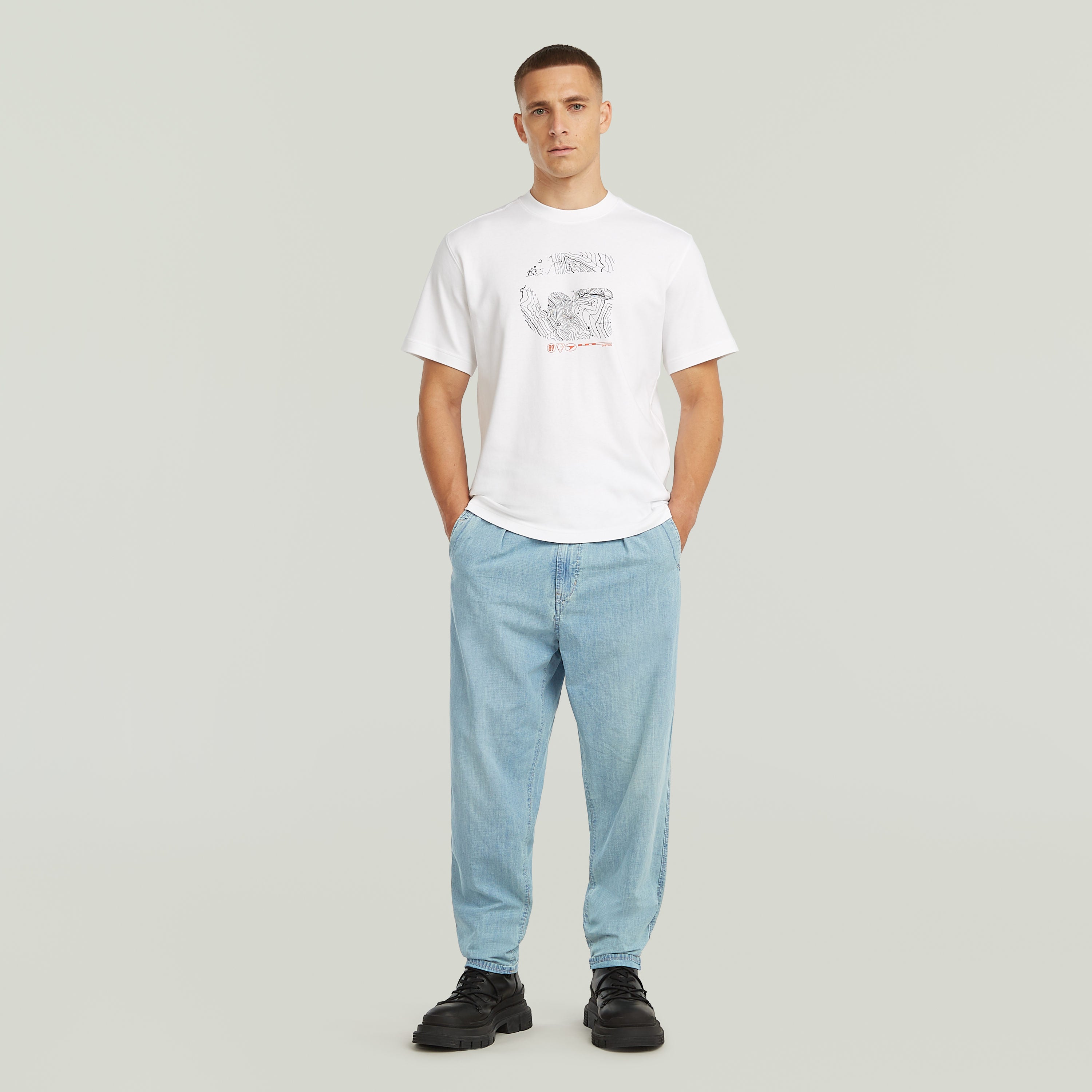 Modelo vistiendo denim relaxed tapered chinos y camiseta blanca con diseño gráfico.