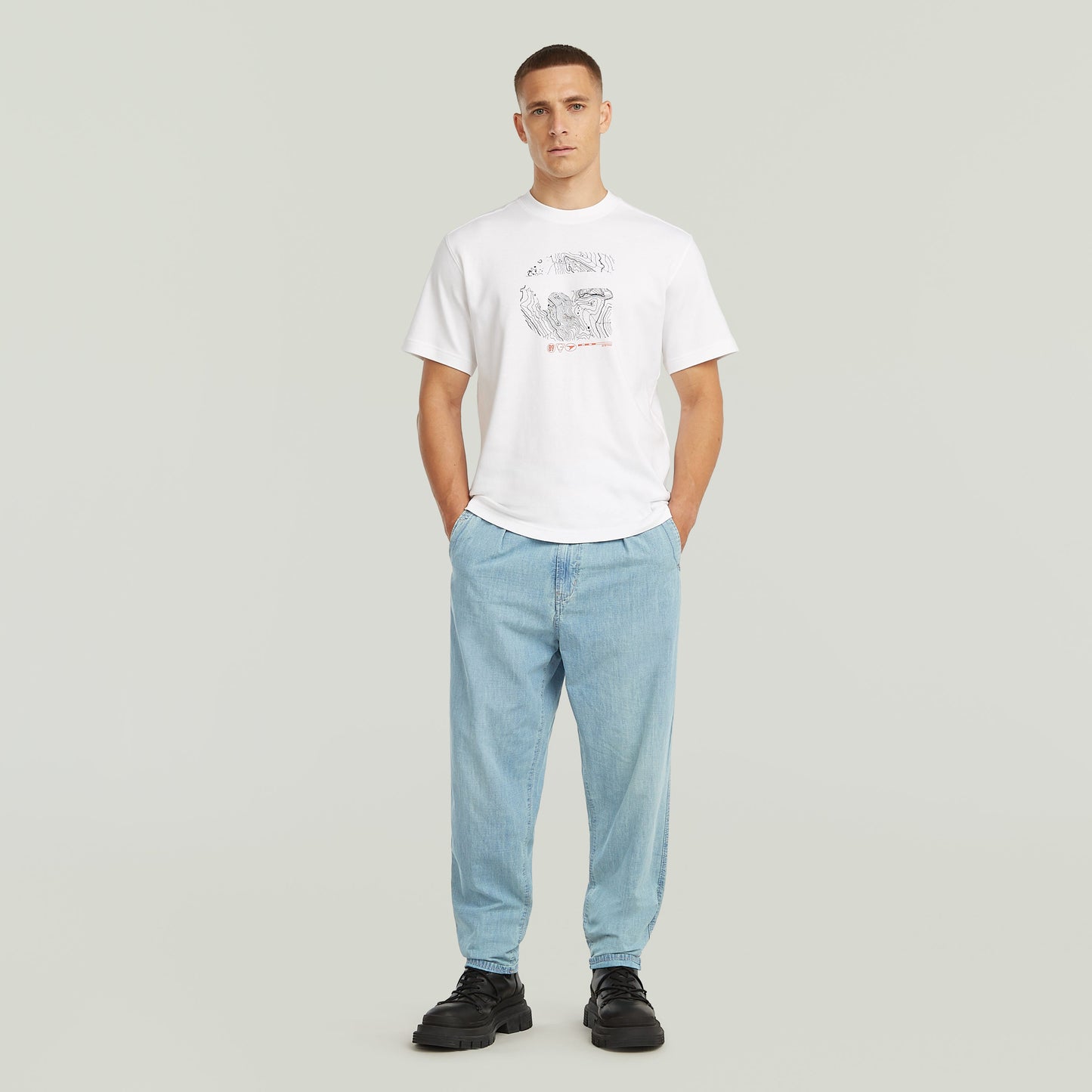 Modelo vistiendo denim relaxed tapered chinos y camiseta blanca con diseño gráfico.