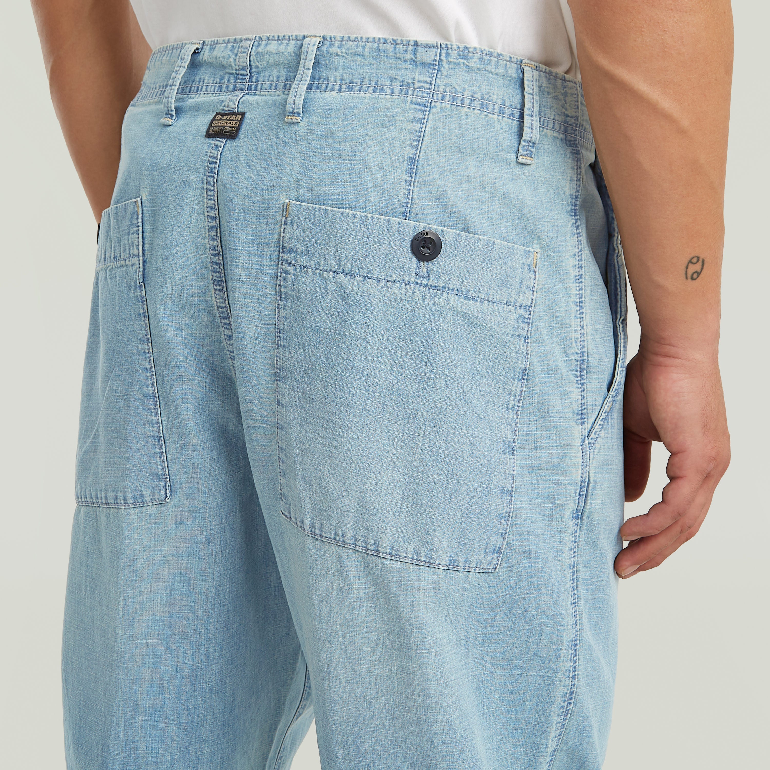 denim relaxed tapered chinos with pleated front and back patch pockets in light blue denim.