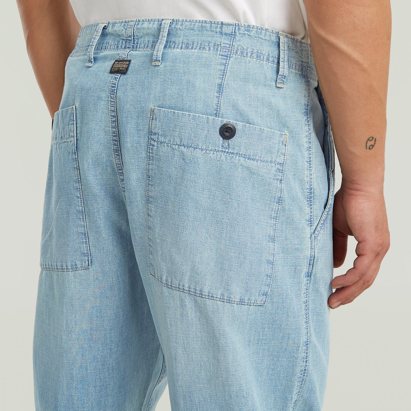 denim relaxed tapered chinos with pleated front and back patch pockets in light blue denim.
