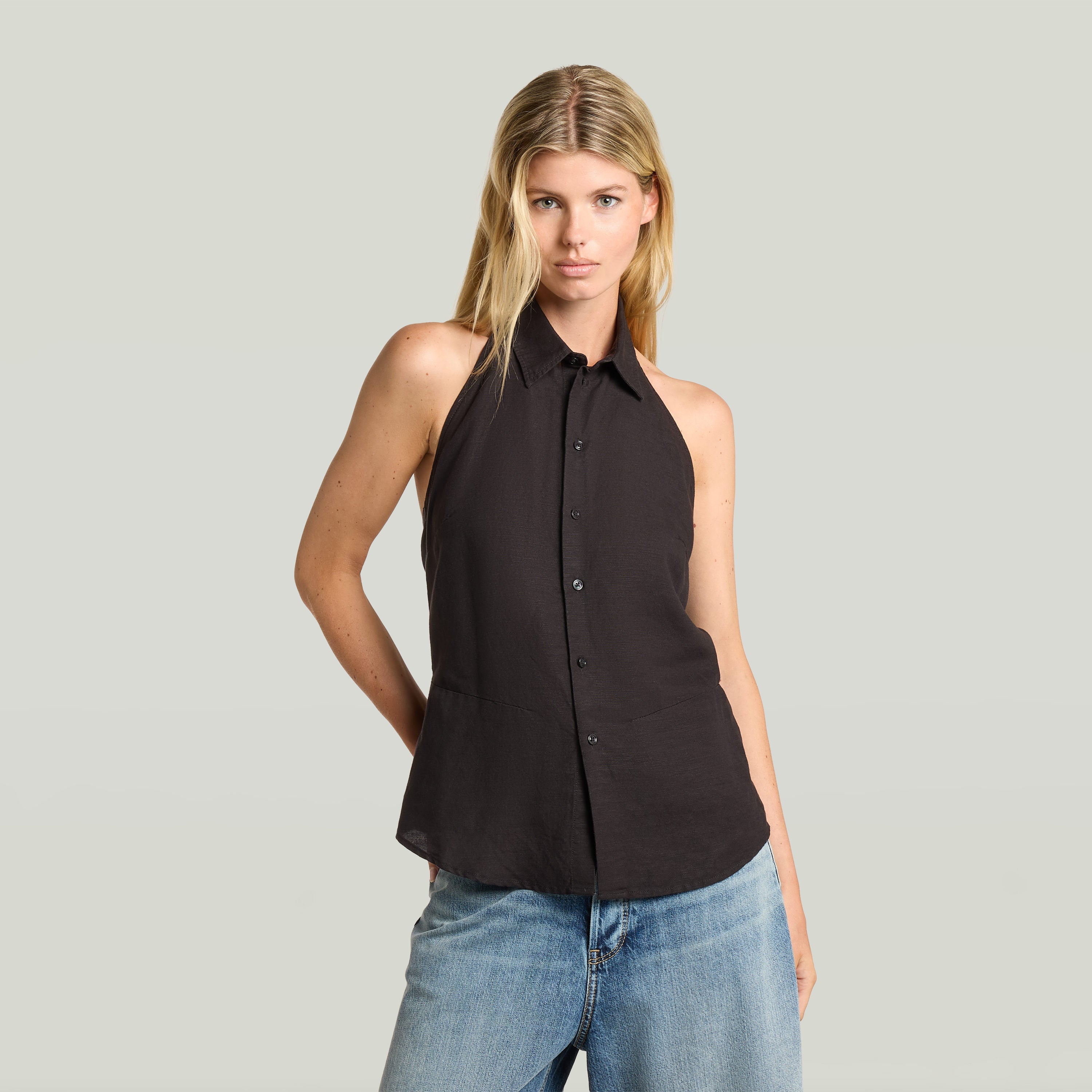 Mujer modelo usando un top halter neck lightweight negro con cuello de camisa y cierre de botones.