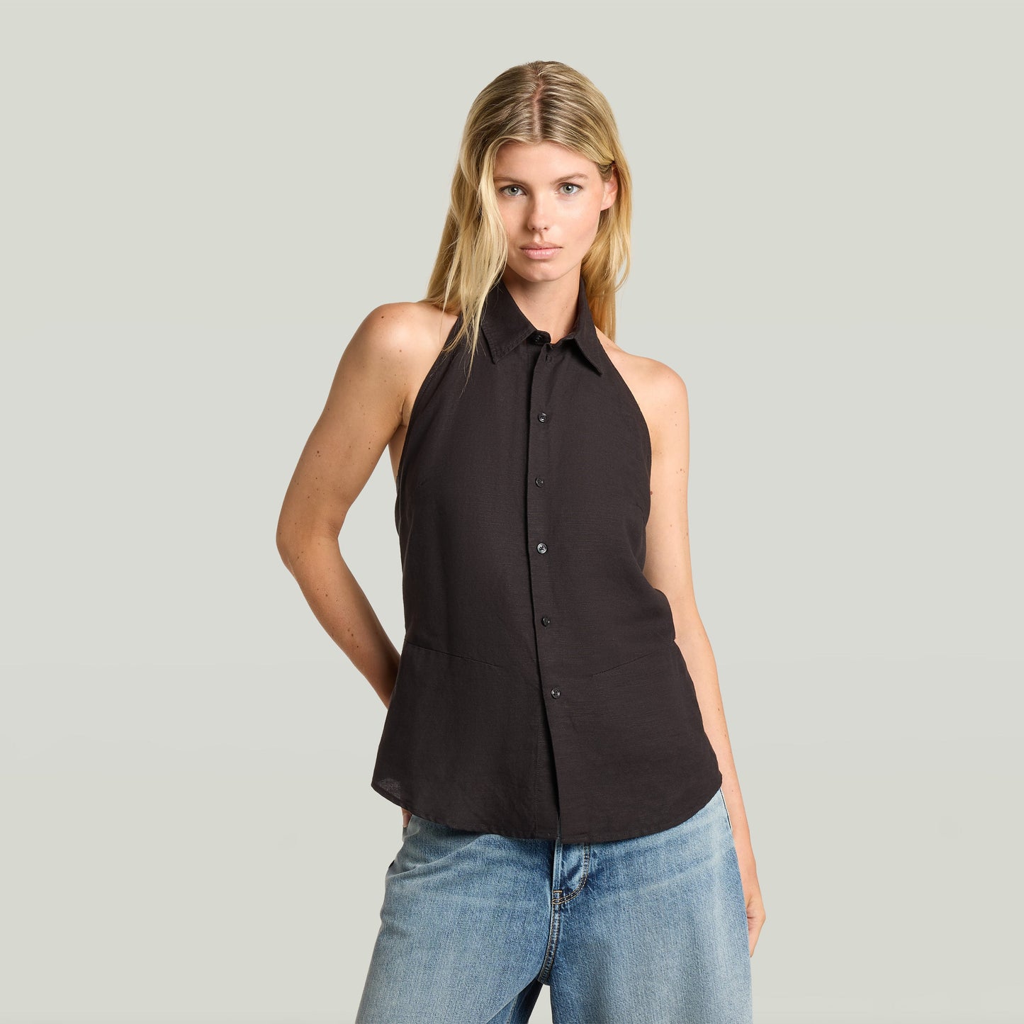 Mujer modelo usando un top halter neck lightweight negro con cuello de camisa y cierre de botones.