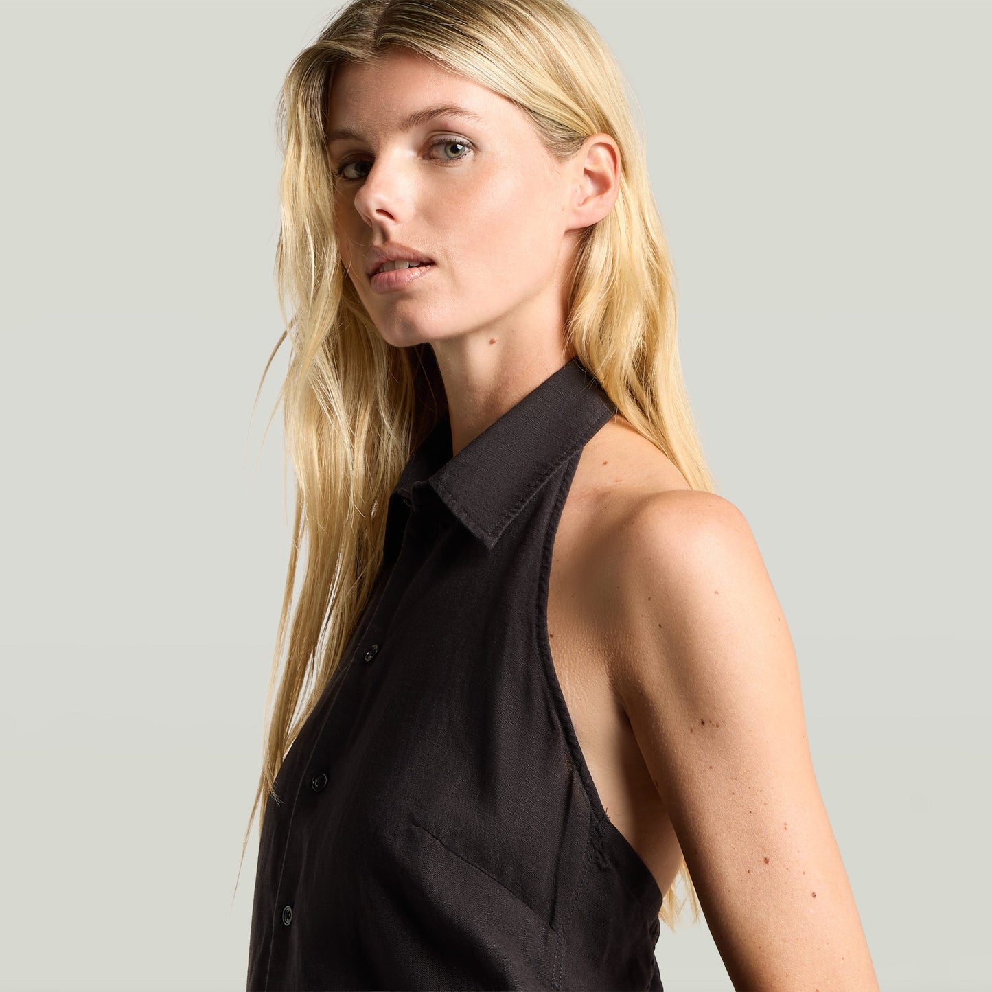 Mujer con top negro de halter neck top lightweight, sin mangas y cuello de camisa, estilo sofisticado.