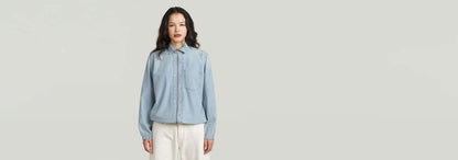 Camisa Relaxed Zip en color azul claro, con cierre de cremallera y diseño clásico moderno.