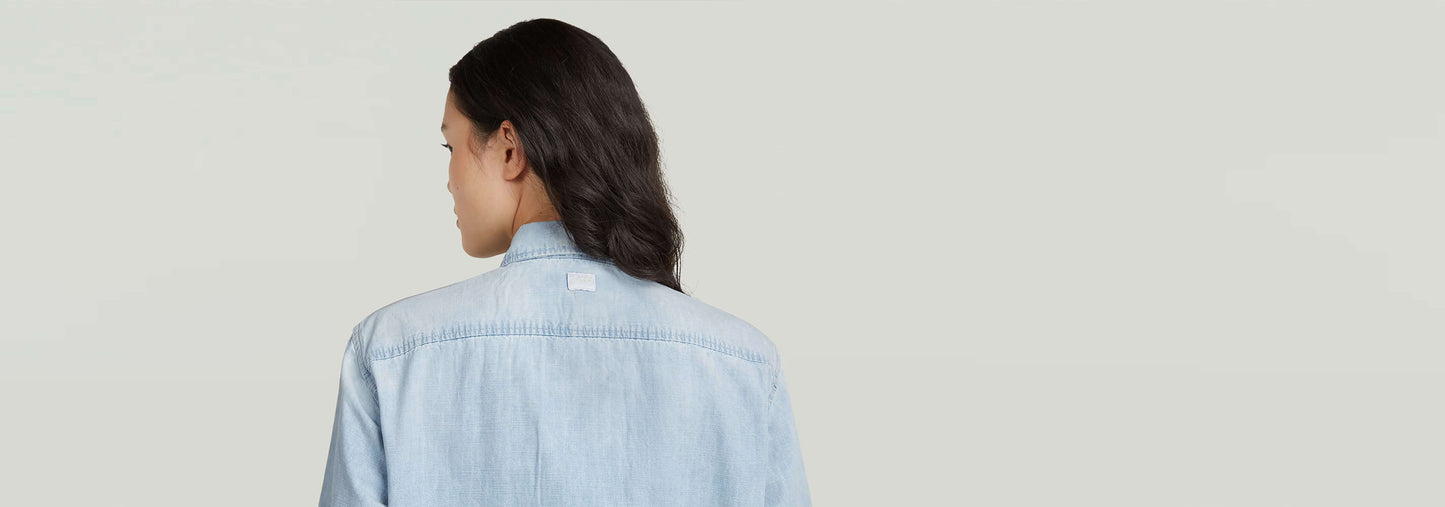 Mujer de espaldas usando la Camisa Relaxed Zip de algodón ligero con diseño moderno.