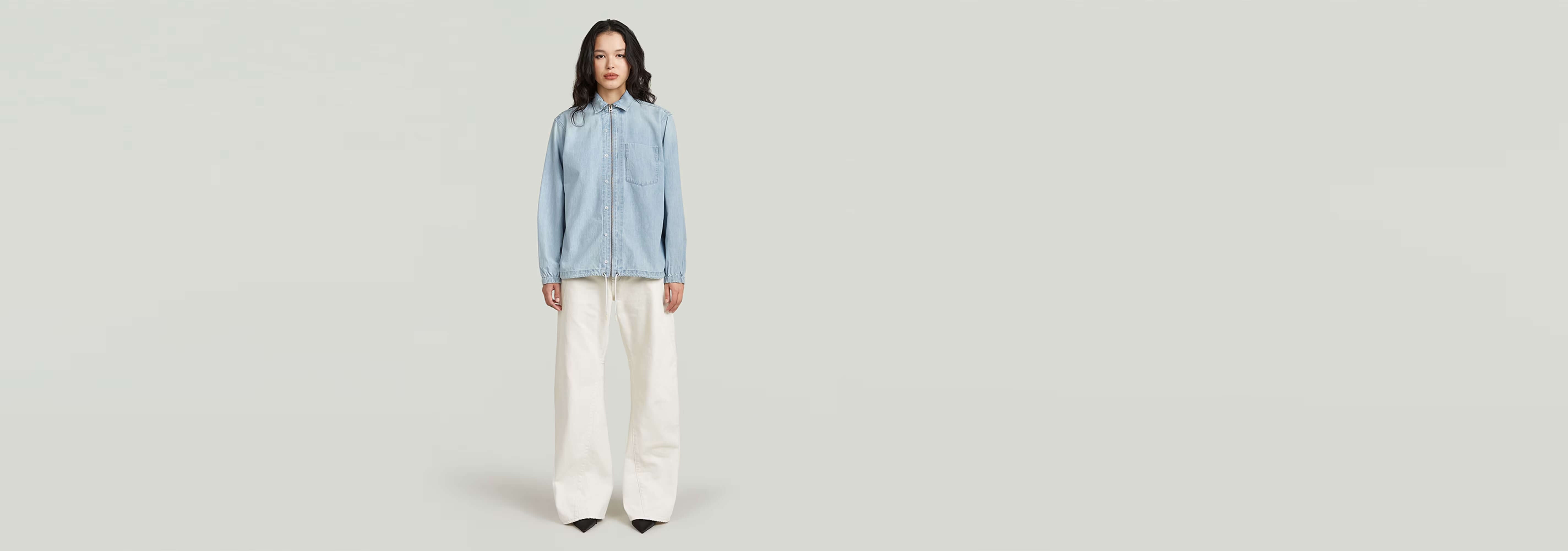 Modelo usando la Camisa Relaxed Zip con cierre de cremallera y pantalones blancos.