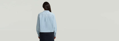 Camisa Resort Boxy Relaxed vista posterior en color azul claro, con corte relajado y cuello clásico.