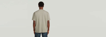 Modelo de espalda usando la Camiseta GS-01 Relaxed en color gris claro, con corte relajado y mangas cortas.