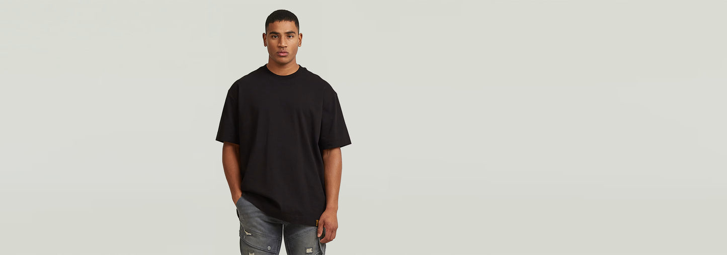 Hombre usando la Camiseta GS-01 Relaxed de corte relajado en color negro, complementado con jeans desgastados.