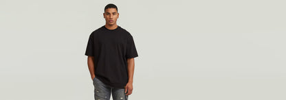 Hombre usando la Camiseta GS-01 Relaxed de corte relajado en color negro, complementado con jeans desgastados.